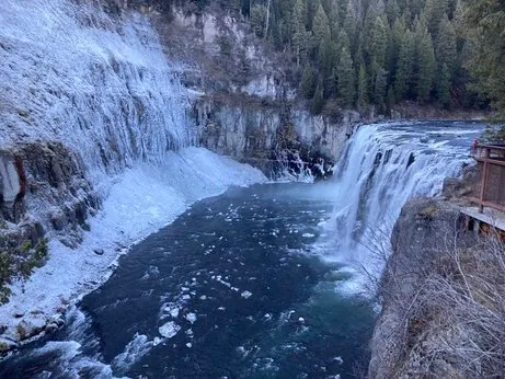 Upper Mesa Falls partially frozen in winter with massive ice formations along the cliff