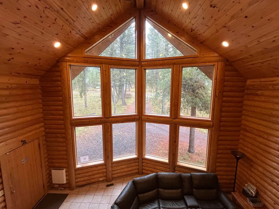Two-story living room windows showcase the surrounding forest — natural light pours in all day
